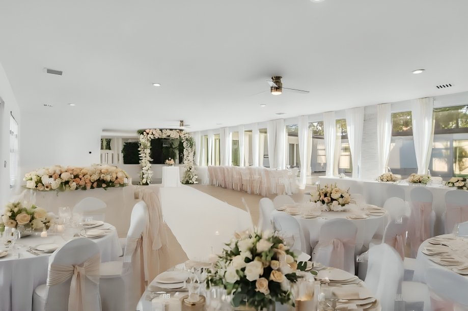 Wedding reception at Villa Verano in Loxahatchee with ivory linens, floral centerpieces and a floral ceremony arch
